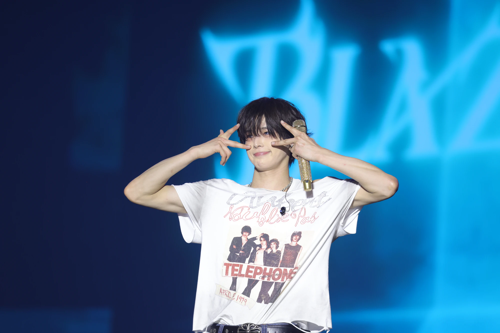 K making a playful pose in a graphic T-shirt.